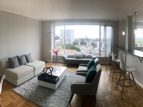 A living room with a white couch, grey armchairs, and a coffee table in front of a large window.