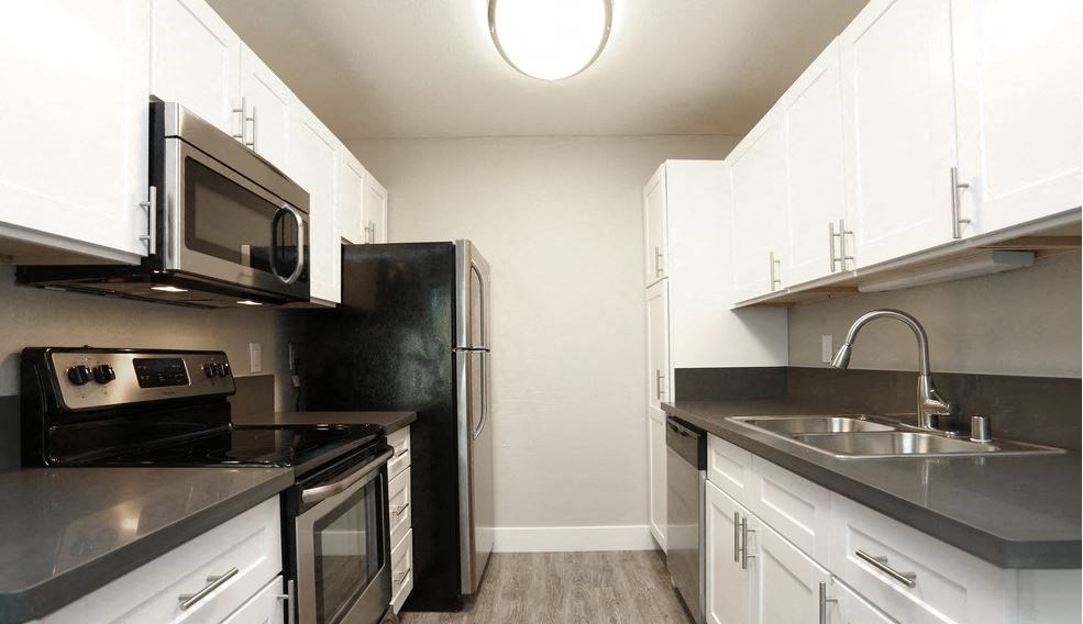 Apartments for Rent in Walnut Creek - Stoneridge - Kitchen with Overhead Lighting, Wood Style Flooring, White Cabinets, and Stainless Steel Appliances