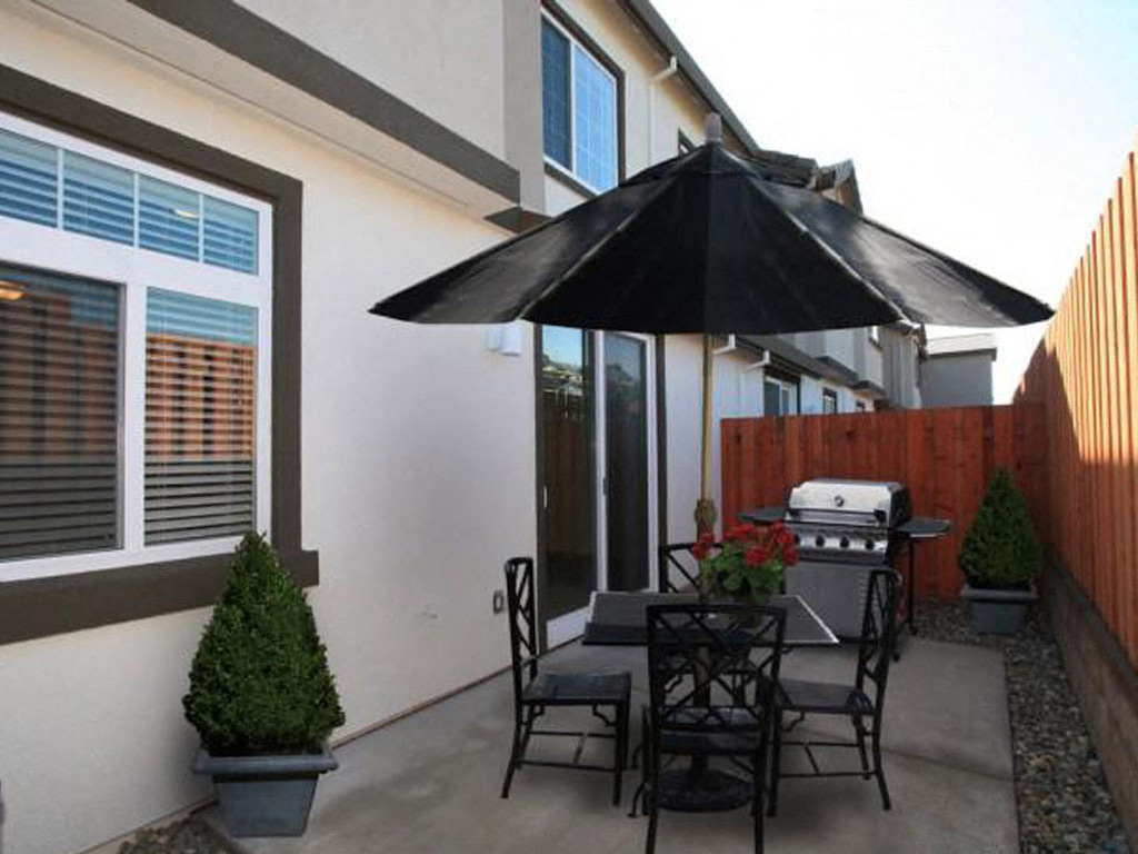Rocklin Apartments - Private Patio With Wood Fence, Sliding Doors, Chairs, And Table With Umbrella.