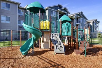 Playground with grass by apt buildings Longmont, Colorado | Copper Peak Apartments - Photo Gallery 9