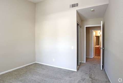 a bedroom with a carpeted floor and a door to a bathroom