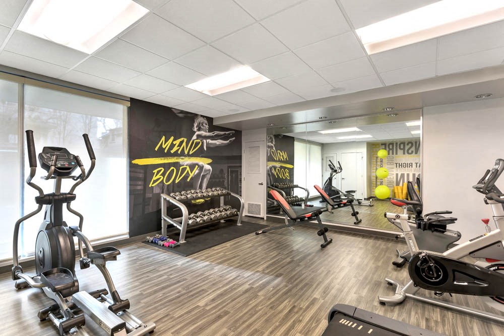 a gym with various exercise machines and weights on a wooden floor