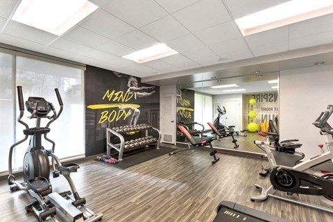 a gym with various exercise machines and weights on a wooden floor
