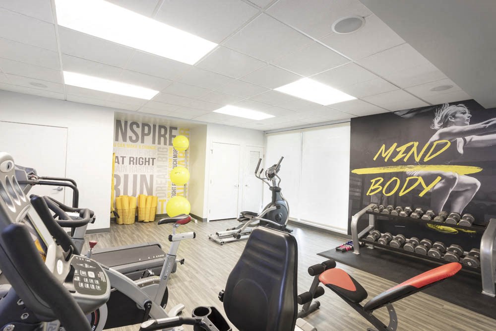 a gym with cardio equipment and a wall mural of gym equipment