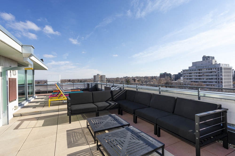 a roof top patio with furniture and a city in the background
