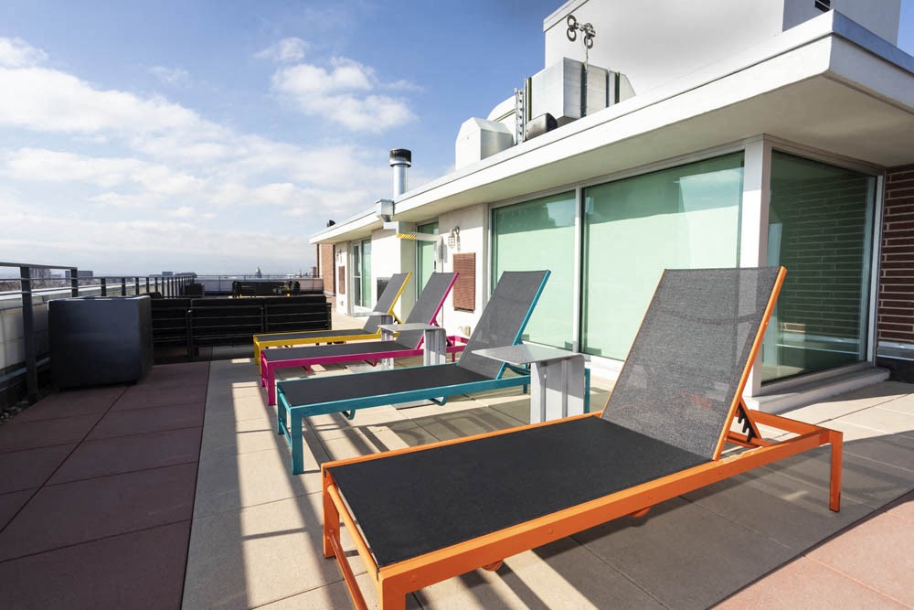 a row of lounge chairs on a rooftop terrace