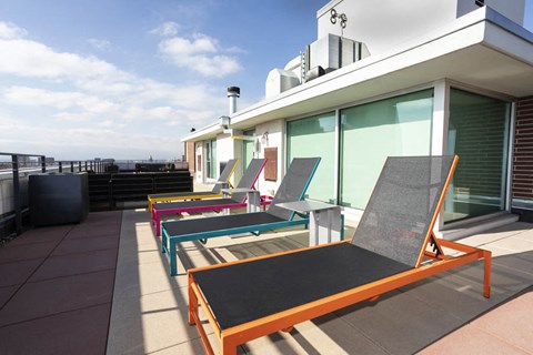 a row of lounge chairs on a rooftop terrace