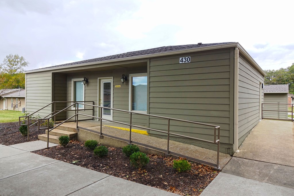 a small green building with steps and a sidewalk