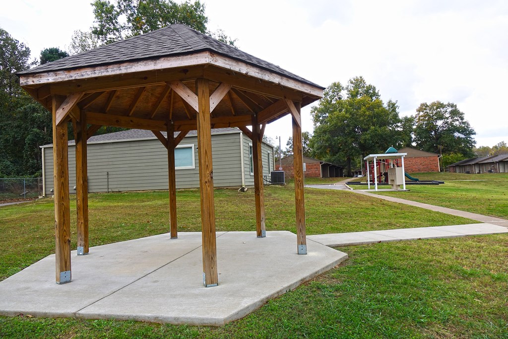 a pavilion sitting on a concrete slab in a park