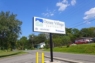 a sign for oconee village apartments on the side of a road