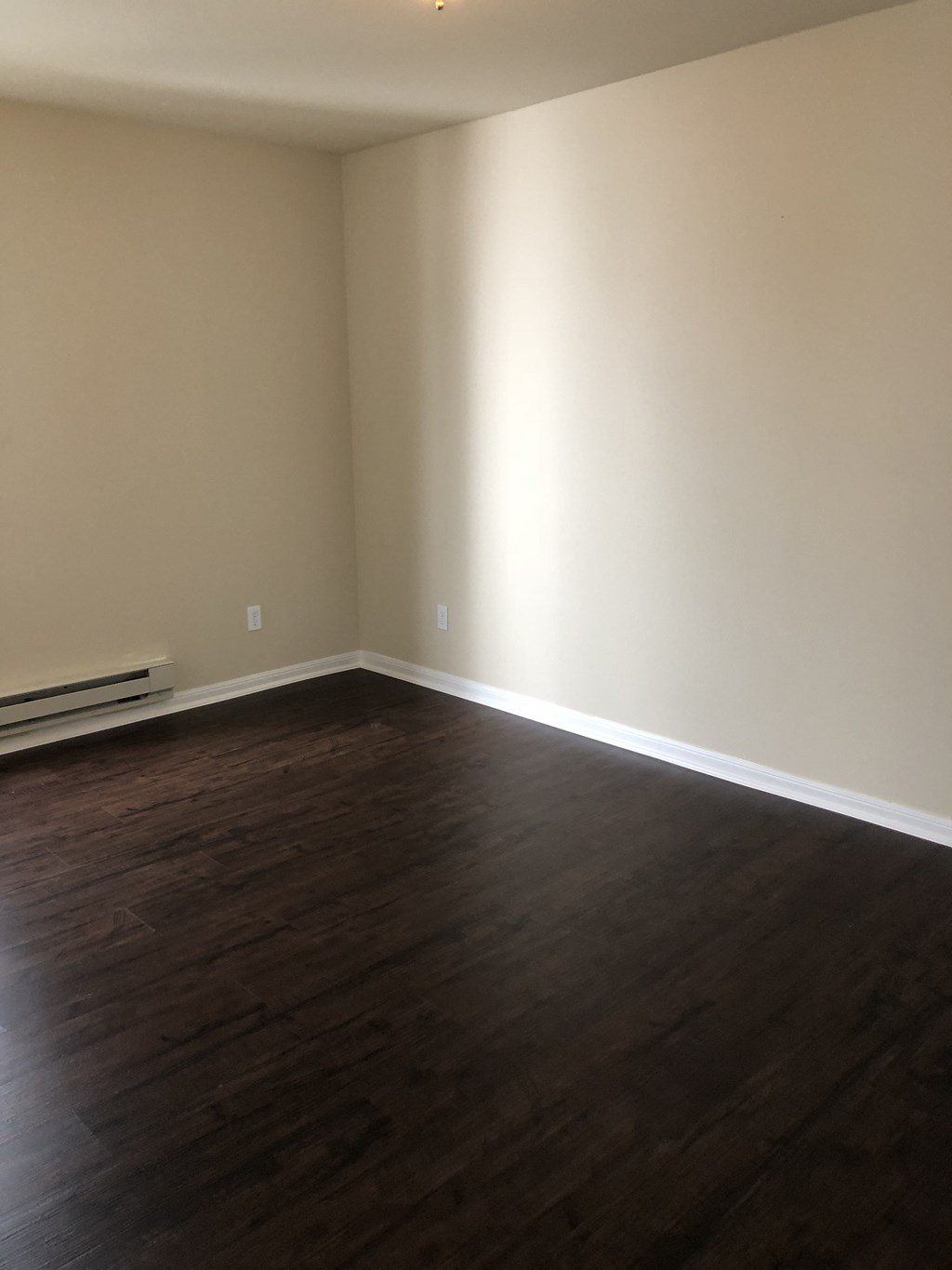 an empty living room with wood floors and white walls