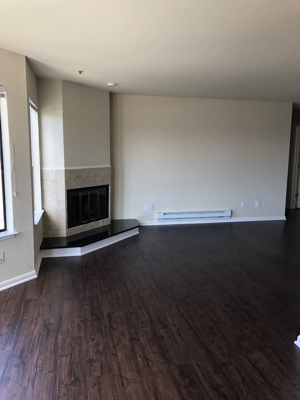 an empty living room with wood floors and a fireplace