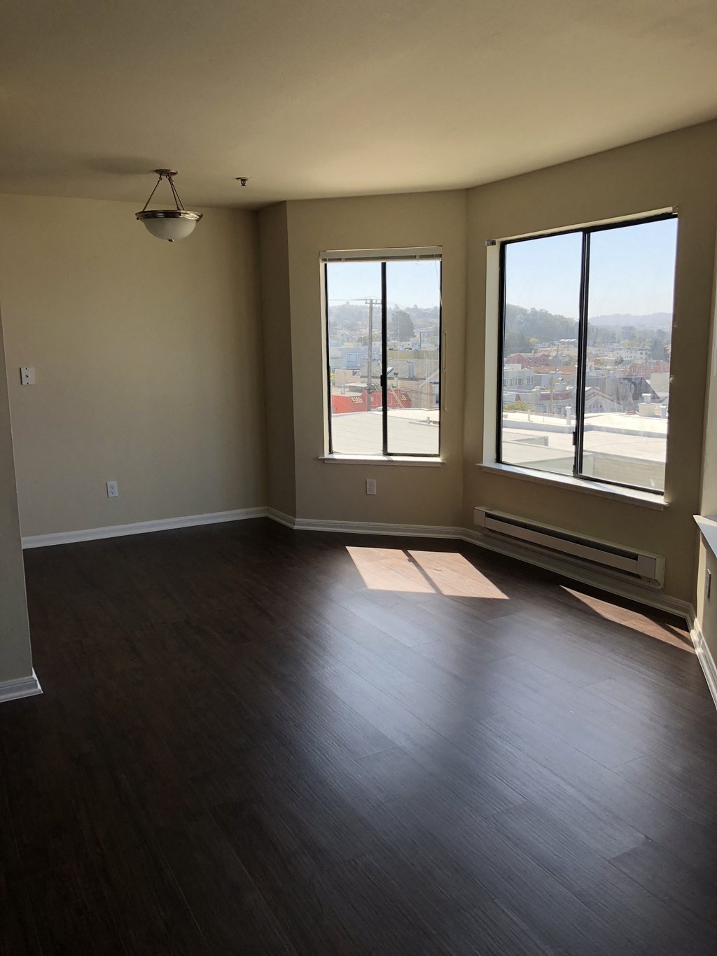 an empty living room with wood floors and large windows