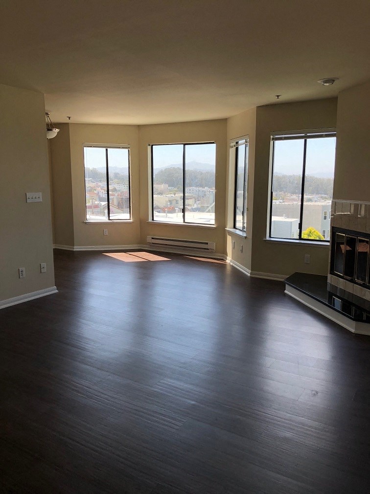 an empty living room with a fireplace and windows