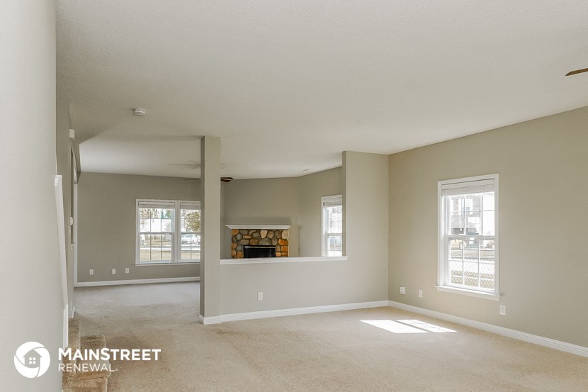 an empty living room with a fireplace in the corner