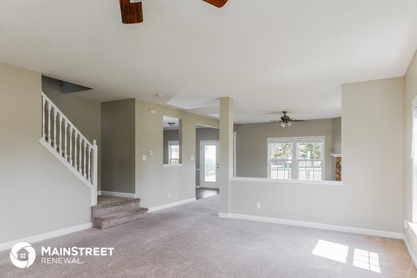 an empty living room with stairs and a window