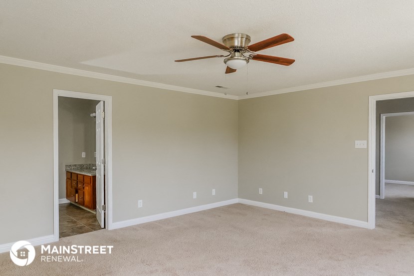 a living room with a ceiling fan and a door to a bathroom