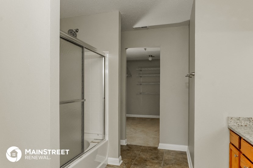 a walk in closet in a bathroom with a mirrored door
