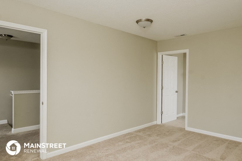 an empty room with a door to a closet and a hallway to a bathroom