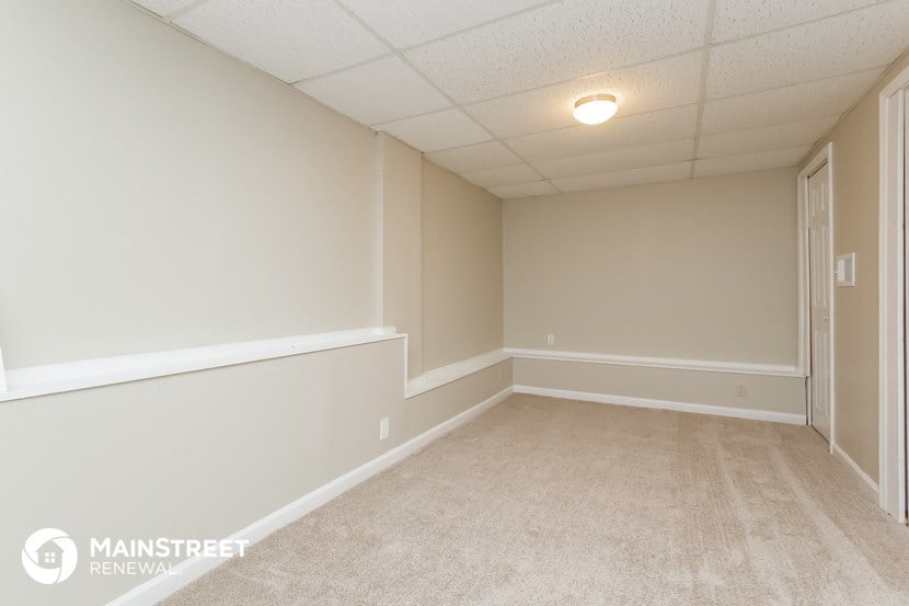 an empty room with white walls and beige carpet
