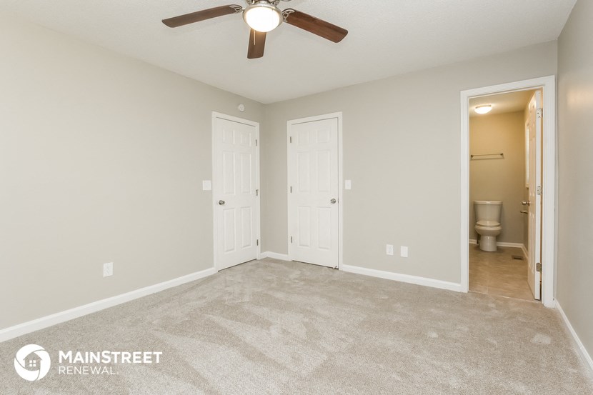 the master bedroom has a carpeted floor and a ceiling fan