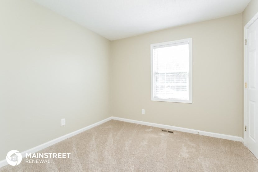 the upstairs bedroom with carpet and a window