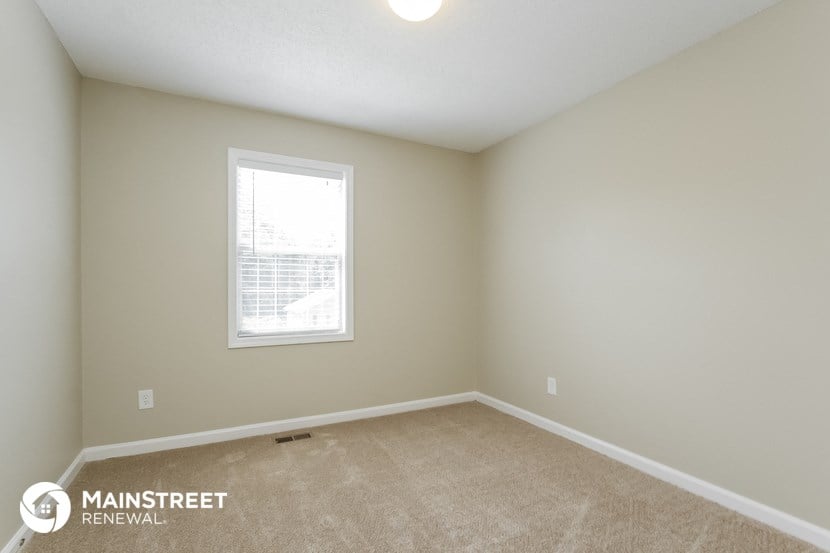 the upstairs bedroom has a large window and beige carpeting