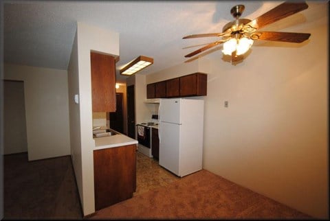 a kitchen with a refrigerator and a ceiling fan
