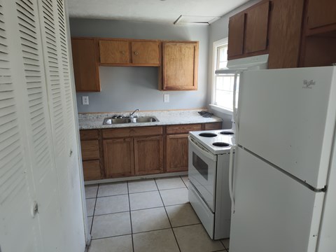 A white refrigerator sits in a kitchen with wooden cabinets.