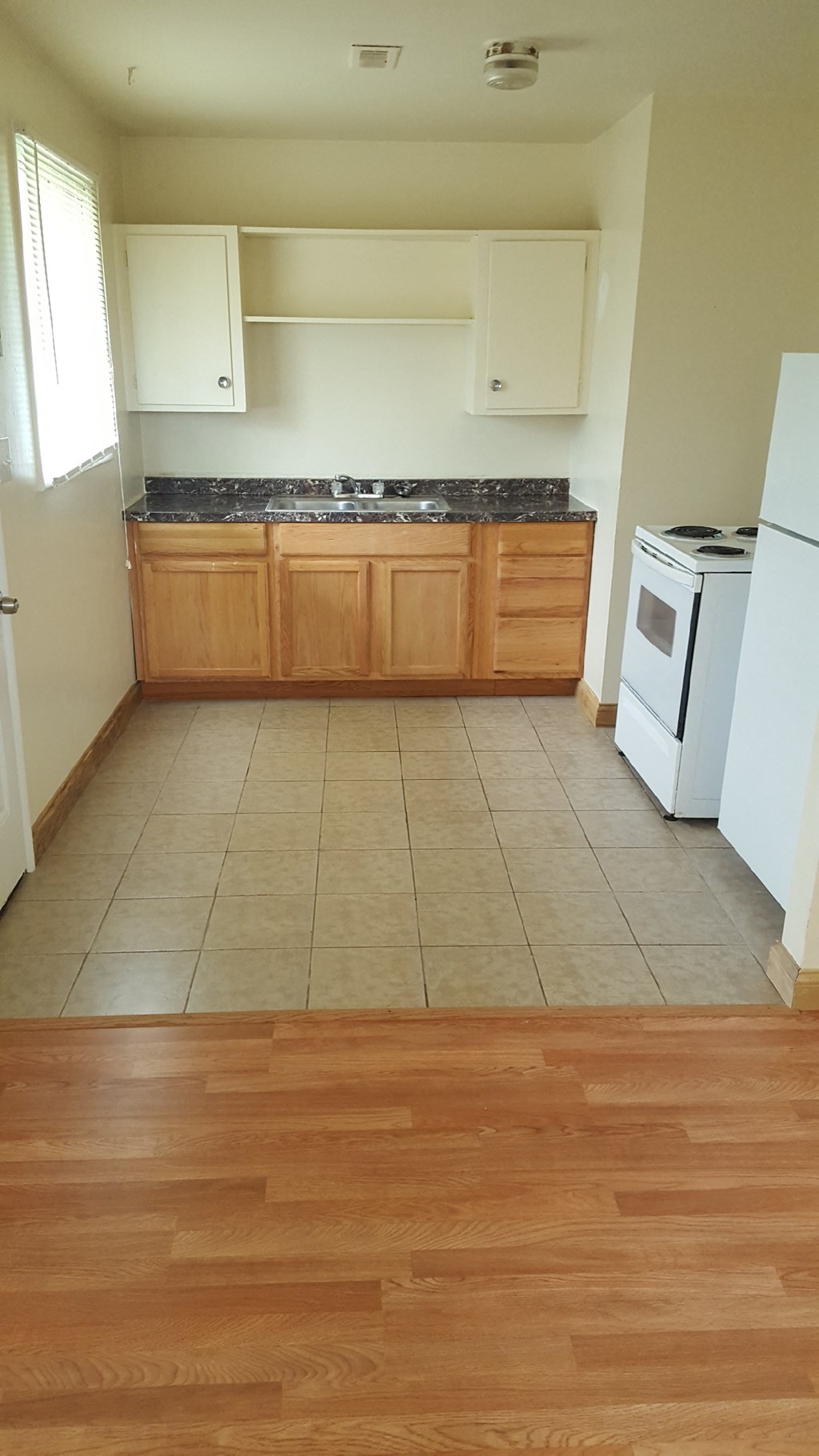 an empty kitchen with wooden floors and white appliances