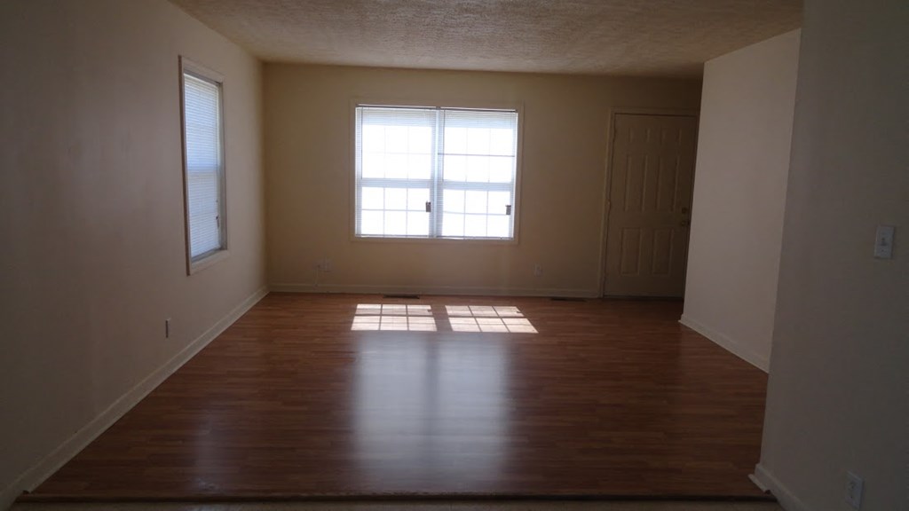 an empty living room with wooden floors and a window