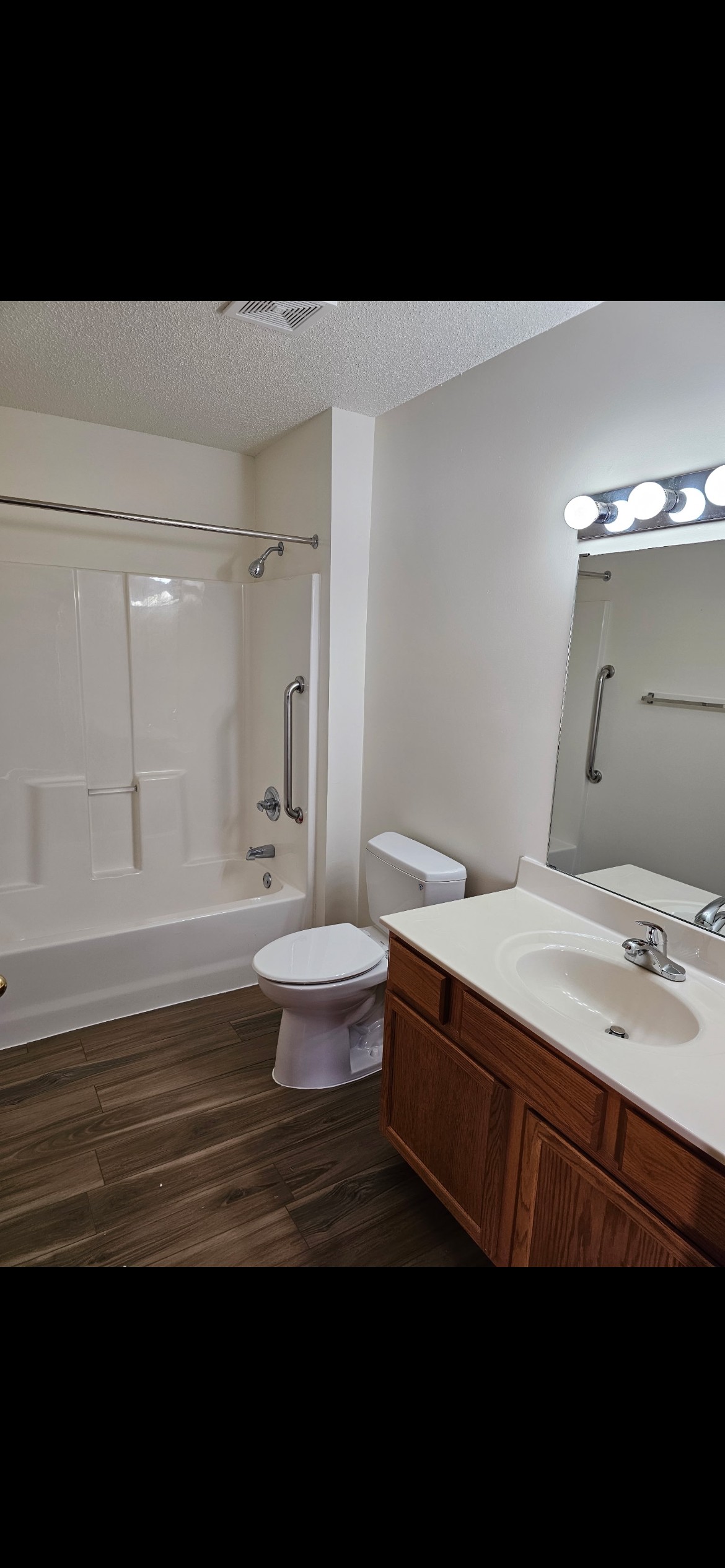 A white toilet sits in a bathroom next to a sink and a bathtub.