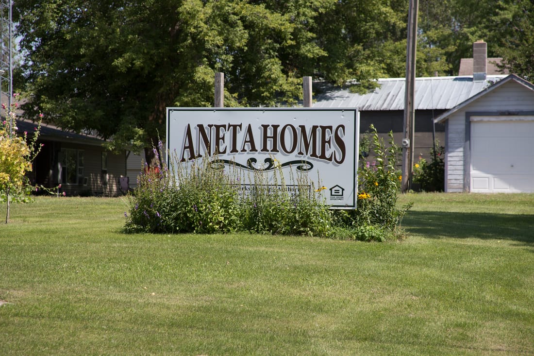 A sign that says Aneta Homes in front of a house.