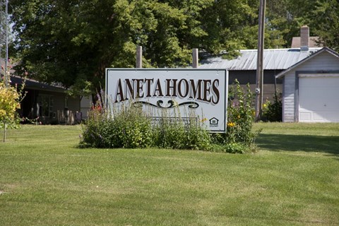 A sign that says Aneta Homes in front of a house.