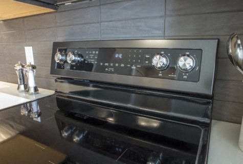 A modern black oven with a digital control panel is installed in a kitchen.
