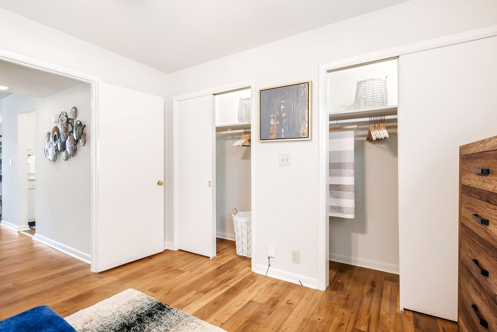 A room with a white door and a white wall with a picture on it.