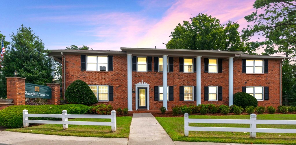 A red brick building with a white fence in front.