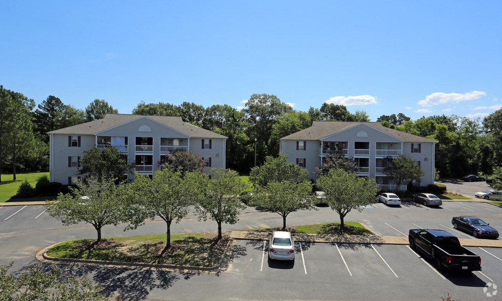 an aerial view of an apartment complex with parking lot and trees