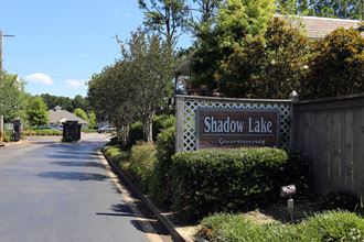 a sign for shadow lake in front of a fence