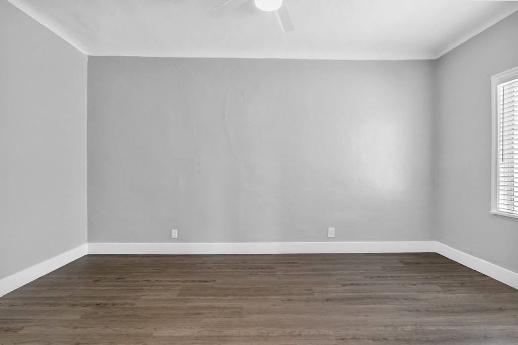 an empty room with white walls and wood floors