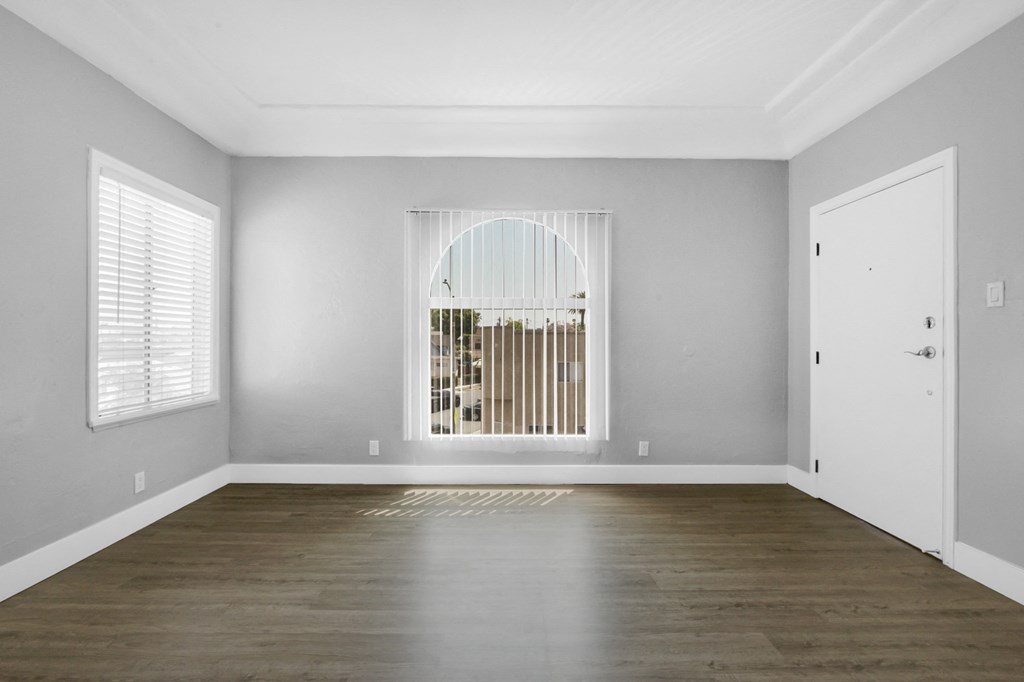 an empty living room with wood floors and a large window