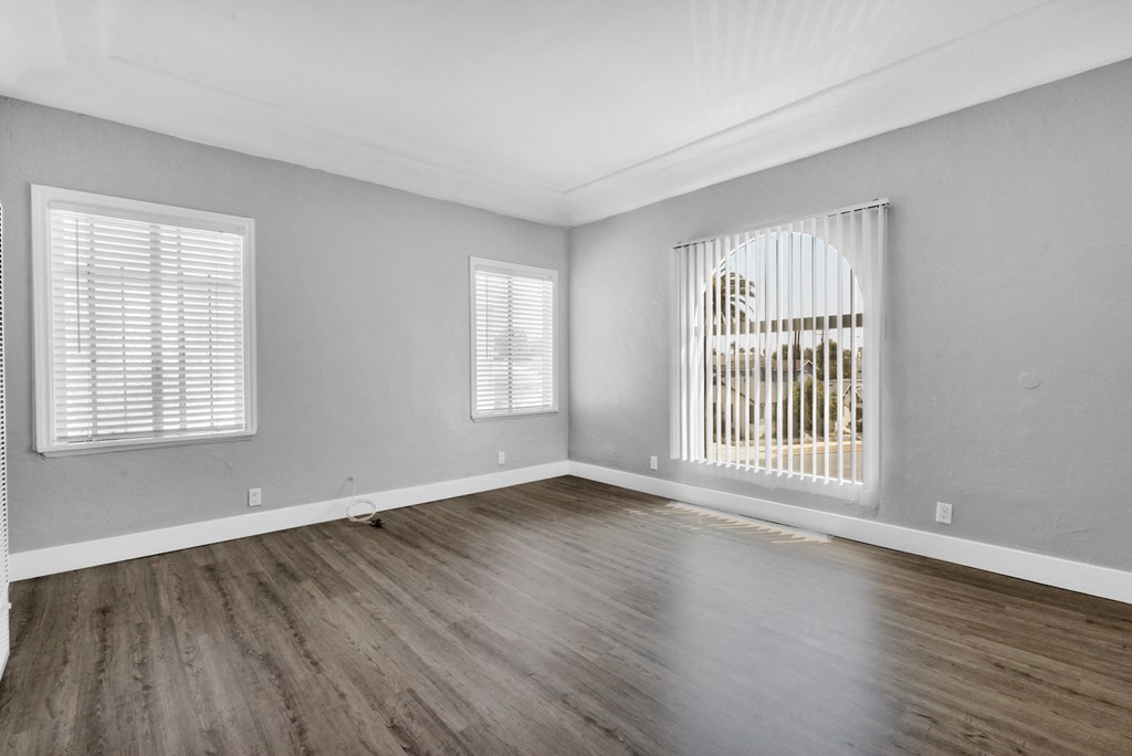 the living room of a new home with wood flooring and a large window