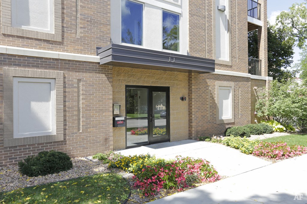a sidewalk in front of a brick building with glass doors