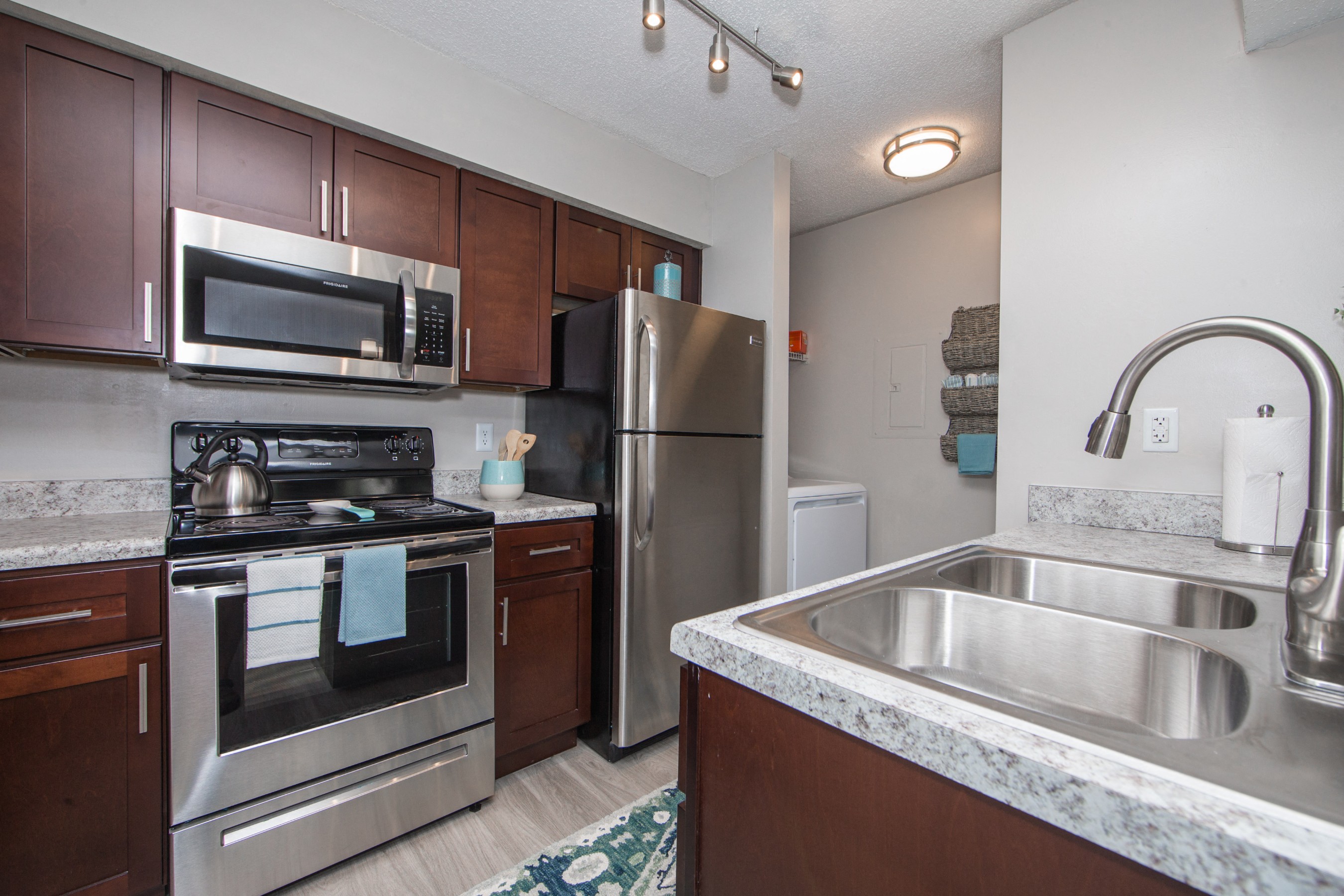 Kitchen with granite countertops stainless microwave electric stove and double sink at St. Croix Apartments in Virginia Beach VA