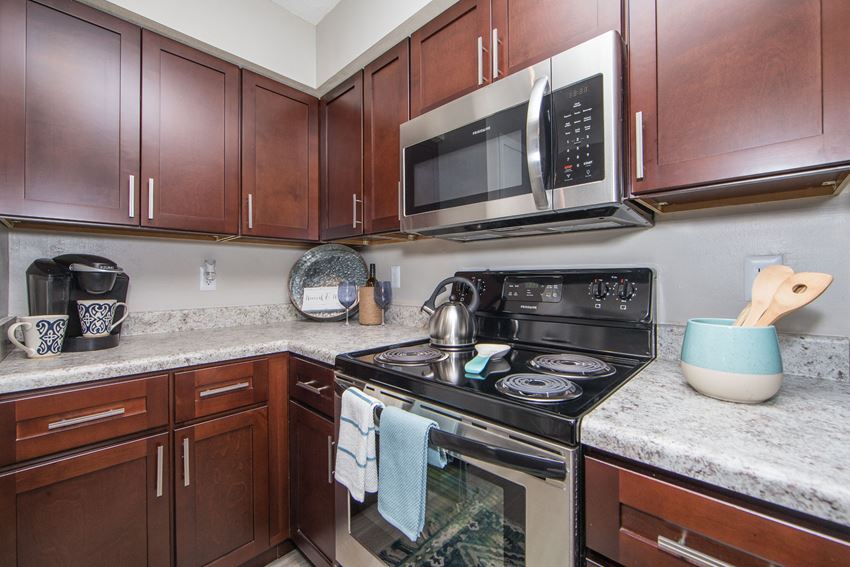 Kitchen with granite countertops stainless microwave and electric stove at St. Croix Apartments in Virginia Beach VA - Photo Gallery 1