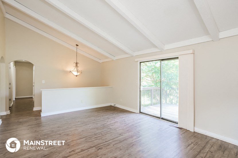an empty living room with a sliding glass door to a balcony