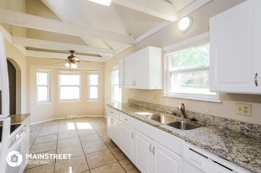 a kitchen with white cabinets and granite counter tops and a sink