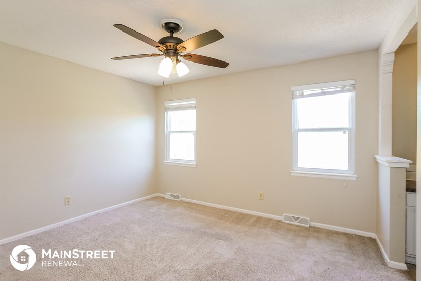 a bedroom with a ceiling fan and two windows