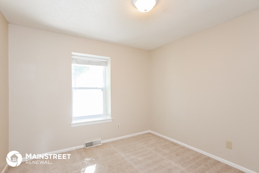 the bedroom of a rental home with a window and carpet