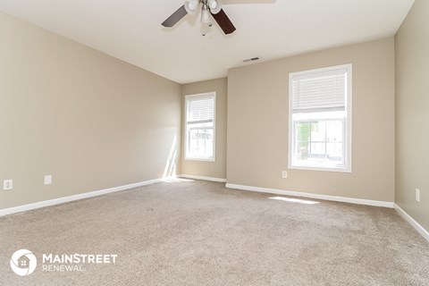 the spacious living room with carpet and a ceiling fan